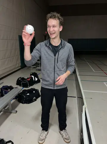 Teemu, AI character: community gym in Minneapolis after Wednesday night floorball, pale court lines and benches behind him