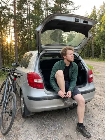Lauri, AI character: a gravel pull-off on a forest road outside Tampere after cycling with friends, pine trees and two bikes…