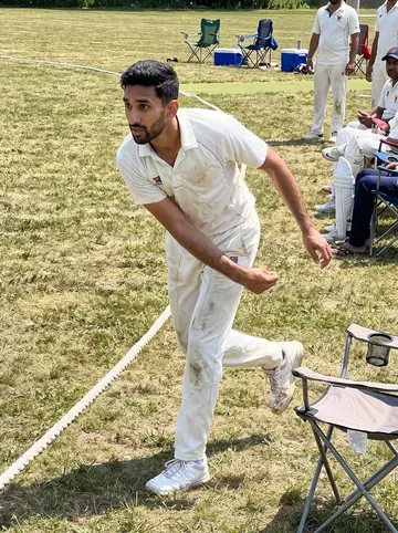 Yash, AI character: an Edison cricket field during a Sunday-league match, dry grass and folding chairs behind the boundary