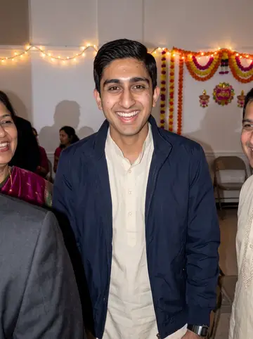 Aditya, AI character: Diwali gathering in a rented Edison community hall, cropped close with relatives partly at the edges of…