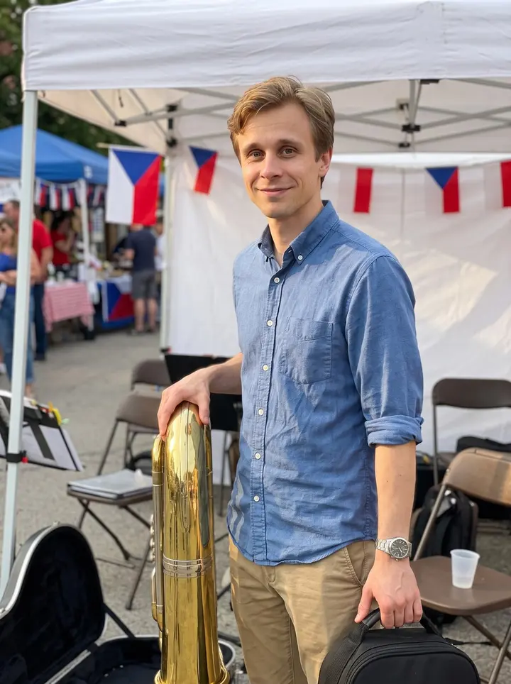 Tomáš, AI character: a small outdoor Czech neighborhood festival in Chicago's Pilsen, standing beside the brass section with…