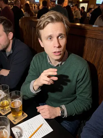 Tomáš, AI character: a crowded Czech beer trivia night at a neighborhood bar in Chicago, dark wood booths and pint glasses…