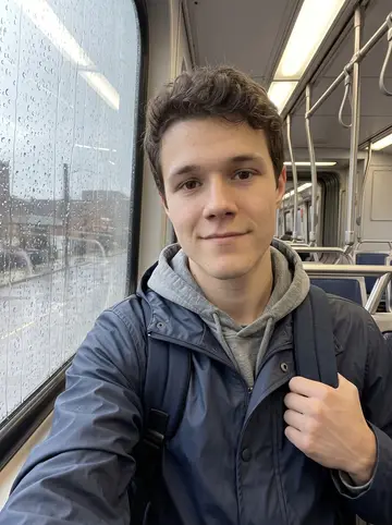 Miloš, AI character: RTA train window seat on the way to a small startup meeting downtown, rain streaking the glass