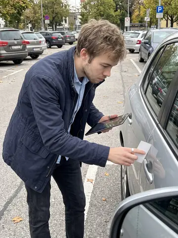 Štěpán, AI character: an outdoor parking area in Vienna while checking a hail-dented car for an insurance claim