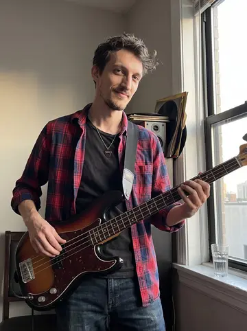 Dariusz, AI character: his Chicago apartment living room near a window, a bass guitar strap over one shoulder, old punk records…