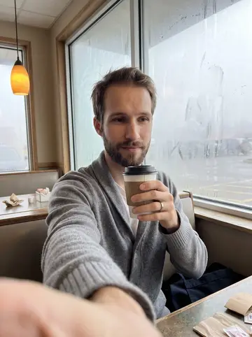 Abram, AI character: the corner booth that catches first light, fogged diner windows behind him after the rush has ended