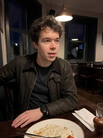 Sjoerd, AI character: a small Inverness steak restaurant with a dark wood table, pepper grinder, and a half-finished plate in…