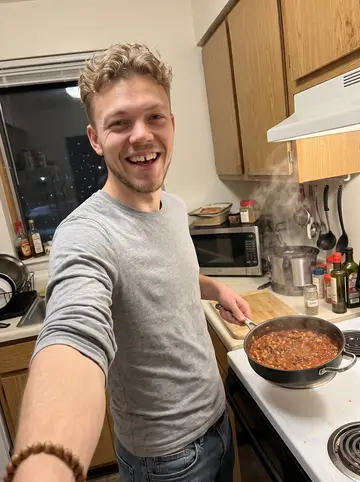 Nick, AI character: his small Duluth apartment kitchen, chili pot on the stove, cumin jar and cutting board on the counter