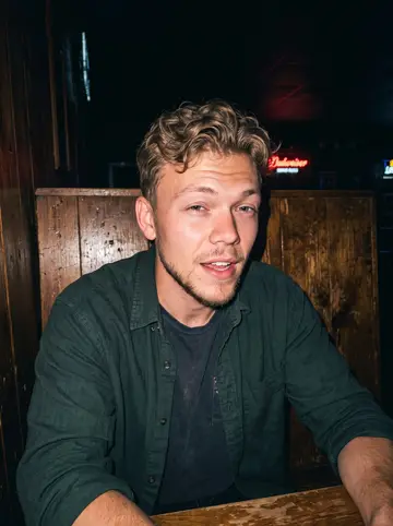 Nick, AI character: a low-key Duluth bar after closing the gear shop, wood booth, old folk record sleeve on the table, neon…