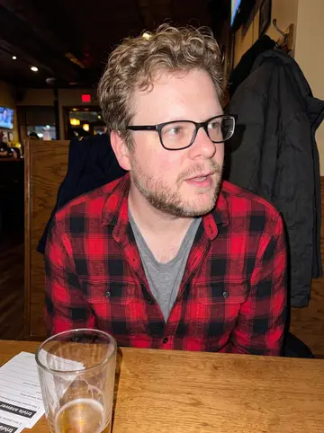 Gary, AI character: a neighborhood trivia night at a warm crowded Minneapolis bar, answer sheets and half-empty pint glasses…
