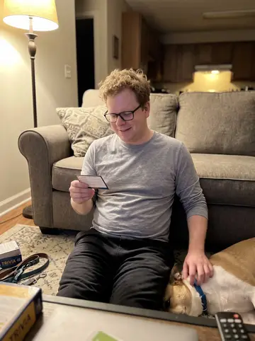 Gary, AI character: his Minneapolis living room late at night, Biscuit stretched out on the rug beside the couch, a trivia…
