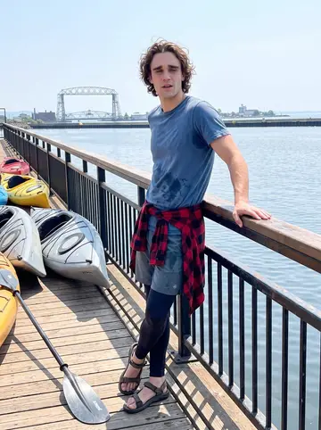 Josiah, AI character: the harbor pier after a Lake Superior paddle, with kayaks pulled up near the railing